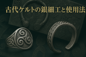 古代ケルトの銀細工をモチーフにしたトリスケル文様のリングと組紐模様のバングルが並ぶ。背景にはケルトの装飾板が配置され、落ち着いたアンティーク調の色合いで撮影されている。