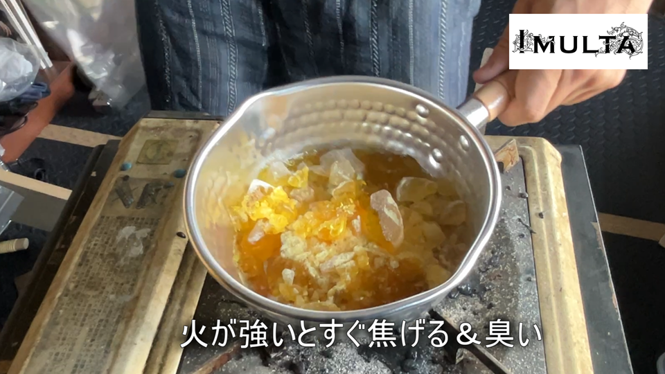 彫金用の松脂を鍋で加熱中。火力が強すぎるとすぐに焦げて嫌な臭いが発生するため、弱火でゆっくり溶かすことが重要であることを示している場面