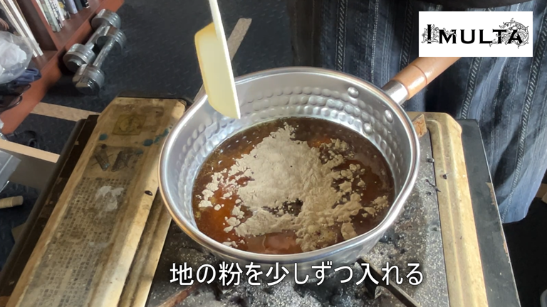 彫金用の松脂を鍋で溶かした後、硬さを調整するために地の粉を少しずつ加えて混ぜている工程。松脂の固定力と耐久性を高めるための重要な作業