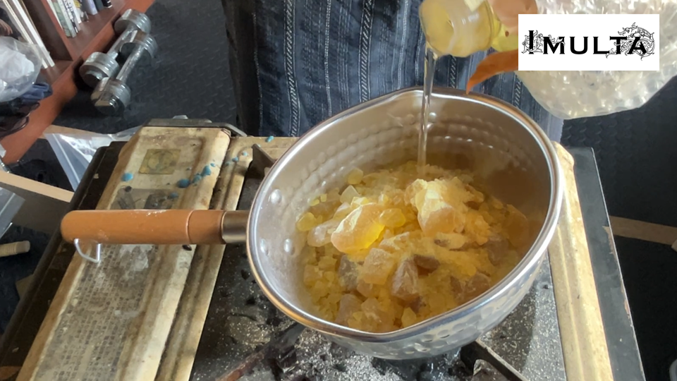 彫金で使用する松脂を鍋に入れ、オリーブオイルを加えて溶かす準備をしている場面