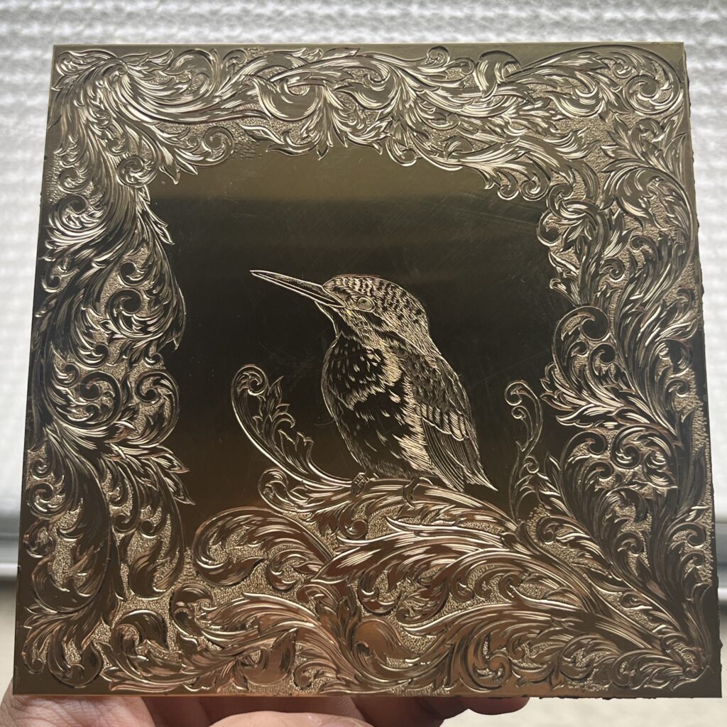 彫金で描かれたカワセミと唐草模様